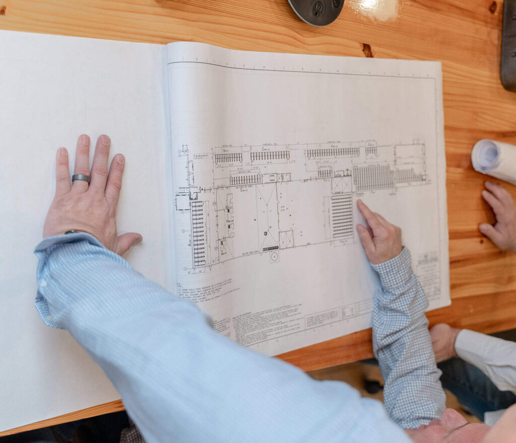 AWS design team reviewing AutoCAD warehouse racking layout blueprints